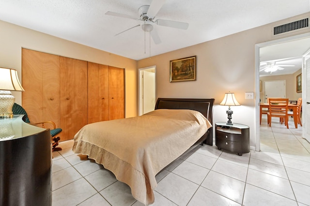 bedroom featuring ceiling fan, light tile patterned floors, and a textured ceiling