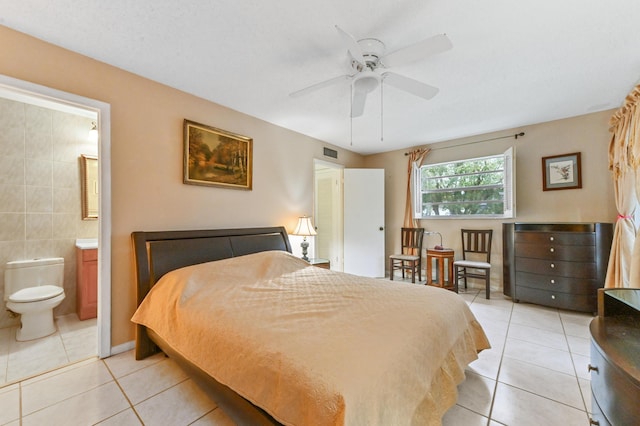 bedroom featuring ceiling fan, tile walls, ensuite bathroom, and light tile patterned flooring