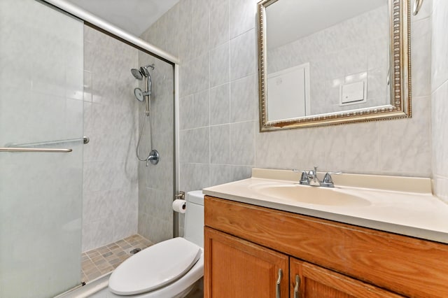 bathroom with toilet, vanity, tile walls, and a shower with door