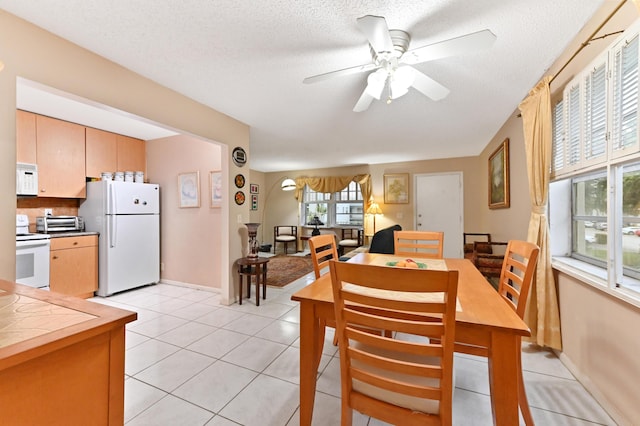 dining area featuring a textured ceiling, ceiling fan, and light tile patterned flooring