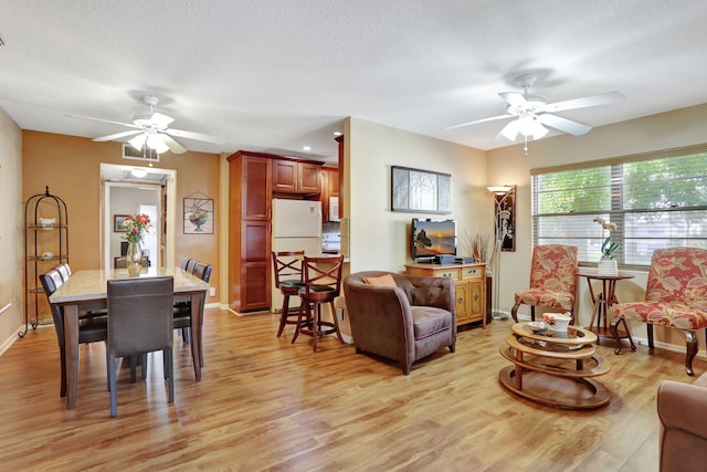 living room featuring a textured ceiling, light hardwood / wood-style flooring, and ceiling fan