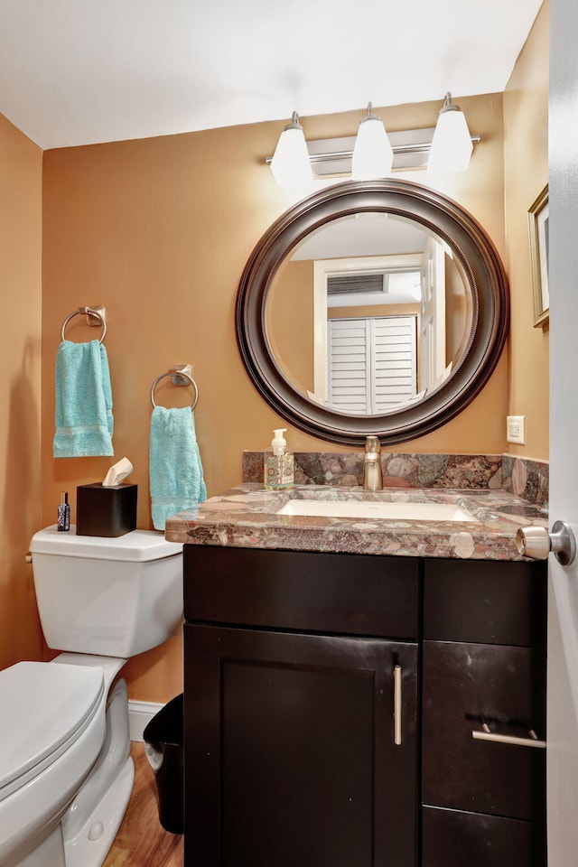 bathroom featuring vanity, wood-type flooring, and toilet