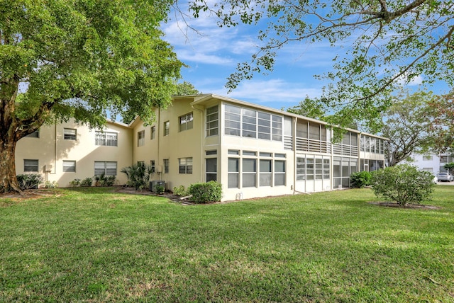 rear view of property with a yard, central AC, and a sunroom