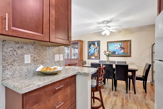 kitchen with a kitchen bar, decorative backsplash, dishwasher, light hardwood / wood-style flooring, and sink