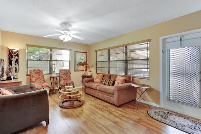 living room featuring ceiling fan, a textured ceiling, and light wood-type flooring