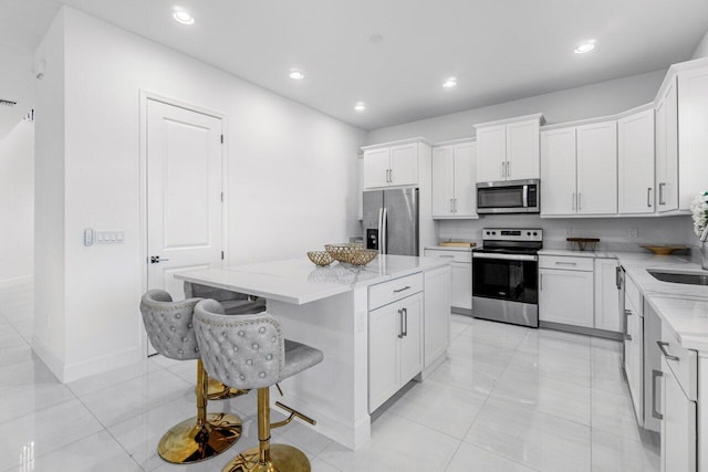 kitchen with a kitchen island, stainless steel appliances, and white cabinetry