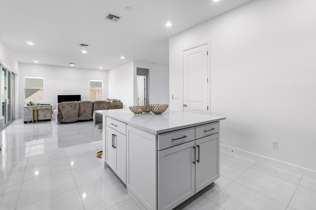 kitchen featuring a center island, light stone counters, gray cabinets, and light tile patterned floors