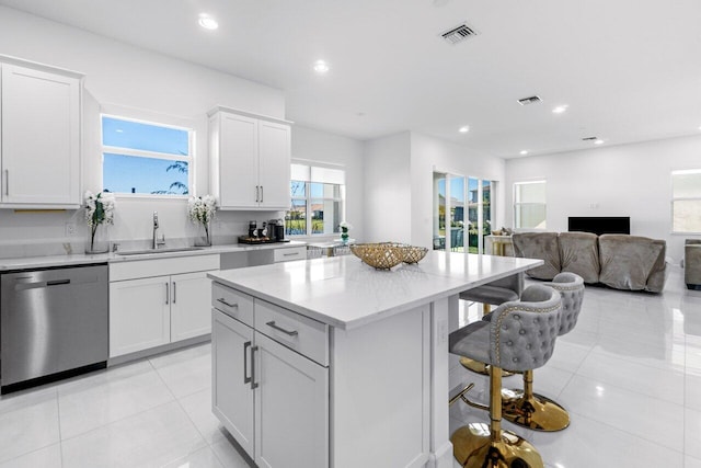 kitchen with stainless steel dishwasher, white cabinets, a center island, and sink