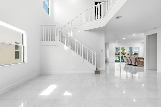 stairs with a towering ceiling and tile patterned floors