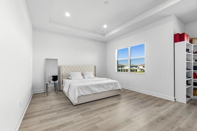 bedroom featuring light wood-type flooring and a tray ceiling