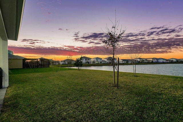 yard at dusk featuring a water view