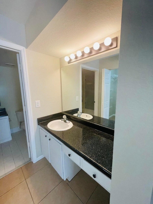 bathroom featuring toilet, a textured ceiling, tile patterned floors, and vanity