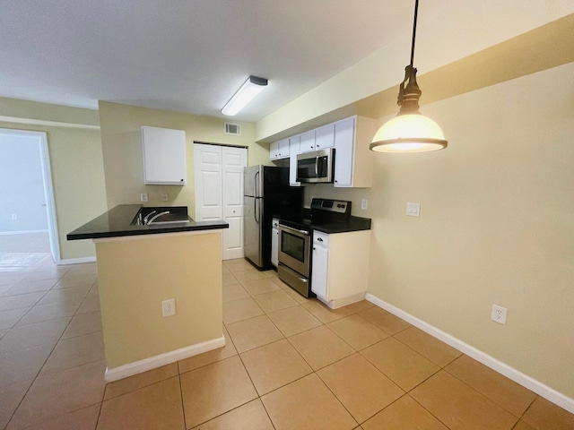 kitchen with appliances with stainless steel finishes, kitchen peninsula, light tile patterned floors, white cabinetry, and decorative light fixtures