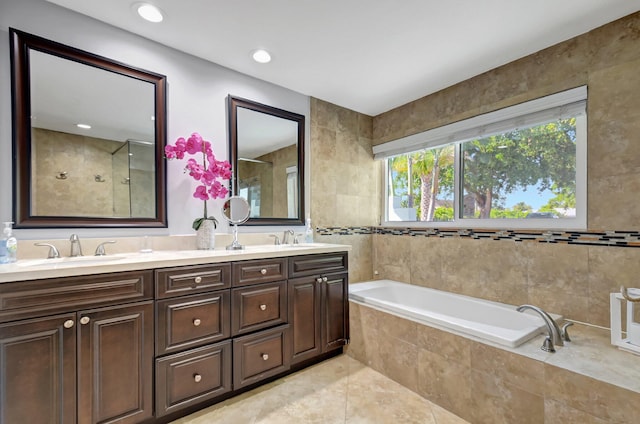 bathroom with a relaxing tiled tub, tile patterned floors, and vanity