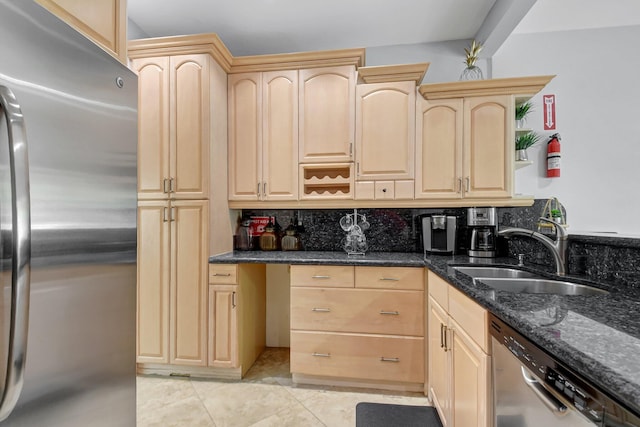 kitchen with sink, light brown cabinetry, dark stone counters, and appliances with stainless steel finishes