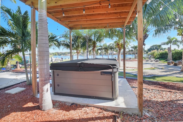 view of patio featuring a hot tub and a water view