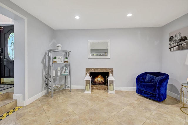 sitting room with a high end fireplace and light tile patterned floors