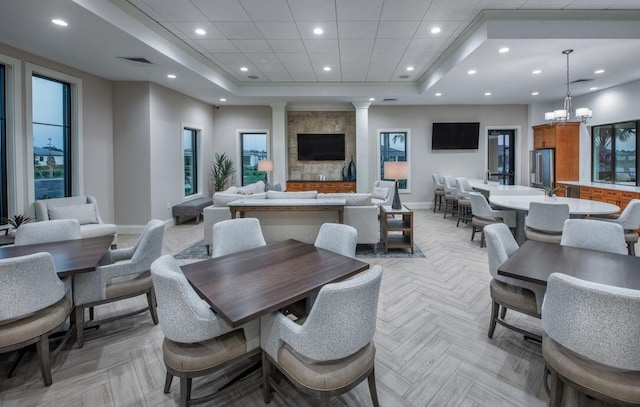 dining room with light parquet floors, an inviting chandelier, and a tray ceiling