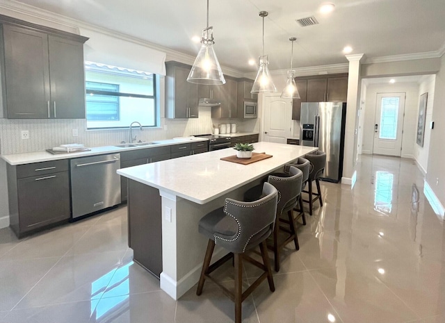 kitchen with a kitchen island, decorative light fixtures, sink, a kitchen breakfast bar, and stainless steel appliances