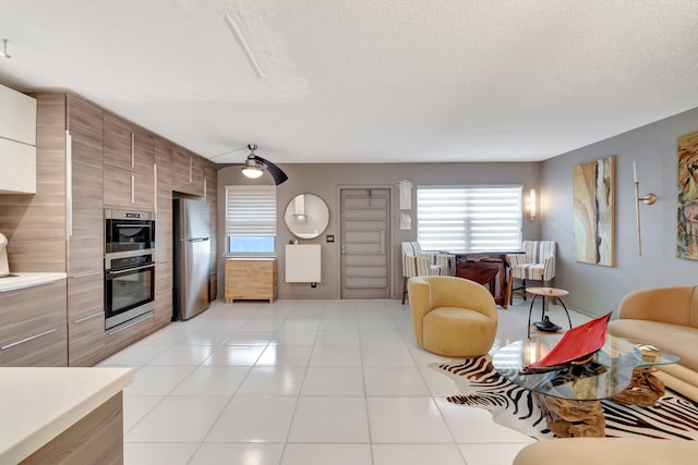 tiled living room with a textured ceiling and ceiling fan