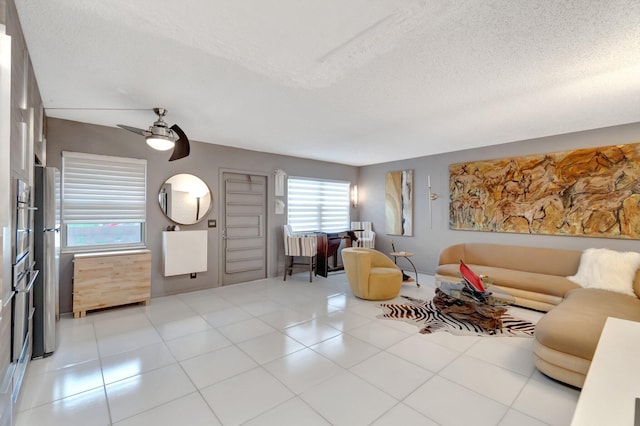 living room with a textured ceiling, ceiling fan, and light tile patterned floors