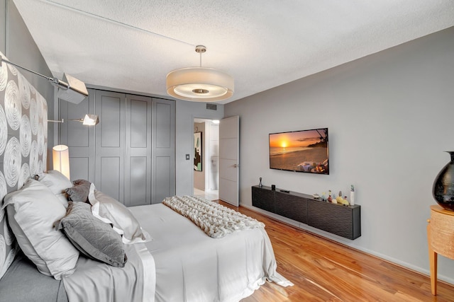 bedroom with light wood-type flooring, a closet, and a textured ceiling