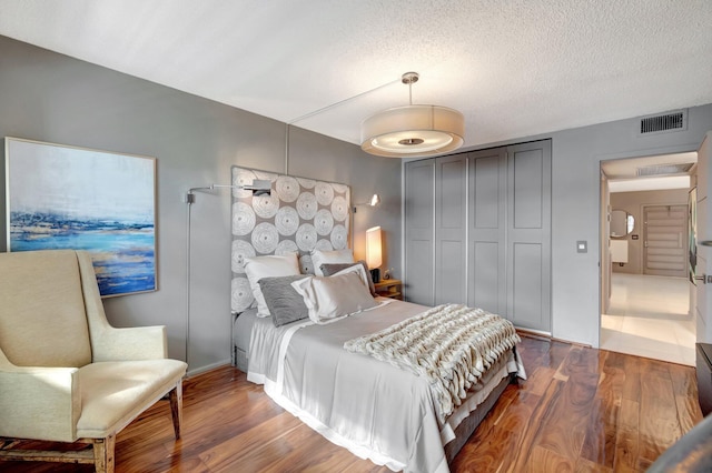 bedroom featuring dark hardwood / wood-style flooring, a closet, and a textured ceiling