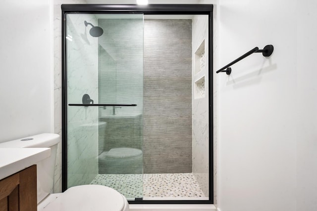 bathroom featuring toilet, an enclosed shower, and vanity