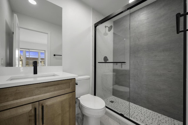 bathroom with toilet, a shower with door, and vanity