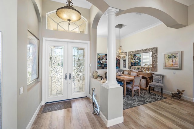 entryway with light hardwood / wood-style floors, ornate columns, ornamental molding, and french doors