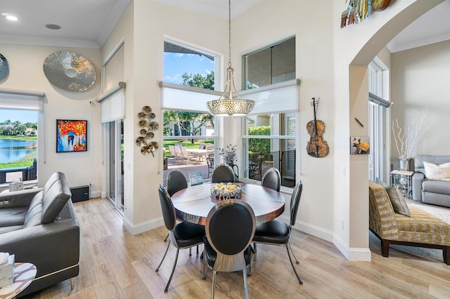 dining space featuring ornamental molding, a high ceiling, light hardwood / wood-style flooring, and a notable chandelier