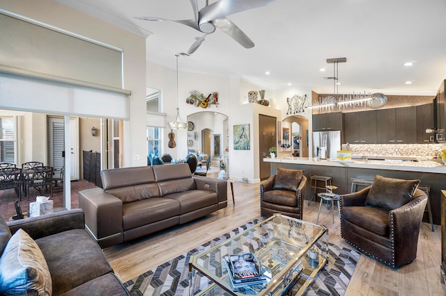 living room featuring ceiling fan, light hardwood / wood-style flooring, ornamental molding, and vaulted ceiling