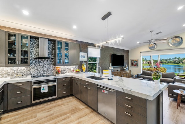 kitchen with crown molding, dark brown cabinets, wall chimney exhaust hood, sink, and stainless steel appliances