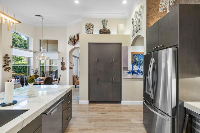 kitchen featuring light hardwood / wood-style floors, ornamental molding, pendant lighting, stainless steel appliances, and light stone counters