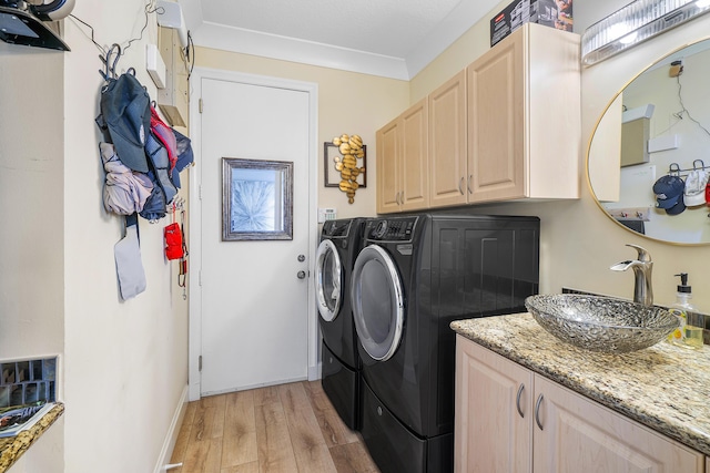 clothes washing area with light hardwood / wood-style floors, sink, ornamental molding, separate washer and dryer, and cabinets