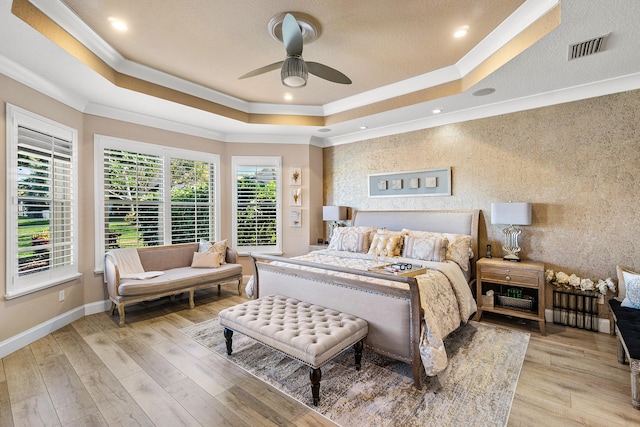 bedroom with ceiling fan, a raised ceiling, light hardwood / wood-style flooring, and crown molding