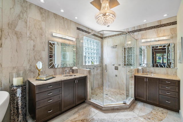 bathroom with a chandelier, vanity, an enclosed shower, and tile walls