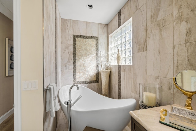 bathroom featuring vanity, a washtub, and tile walls