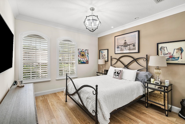 bedroom with light hardwood / wood-style flooring, crown molding, and a notable chandelier