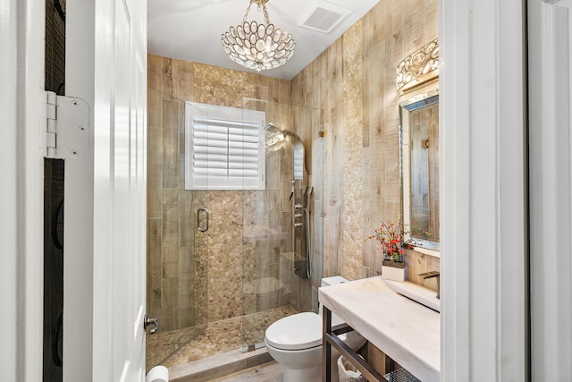 bathroom featuring a shower with shower door, toilet, and a notable chandelier