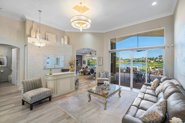 living room featuring light wood-type flooring, a water view, ceiling fan, and ornamental molding