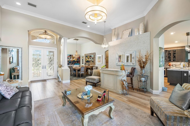 living room featuring light hardwood / wood-style floors, a chandelier, crown molding, and french doors