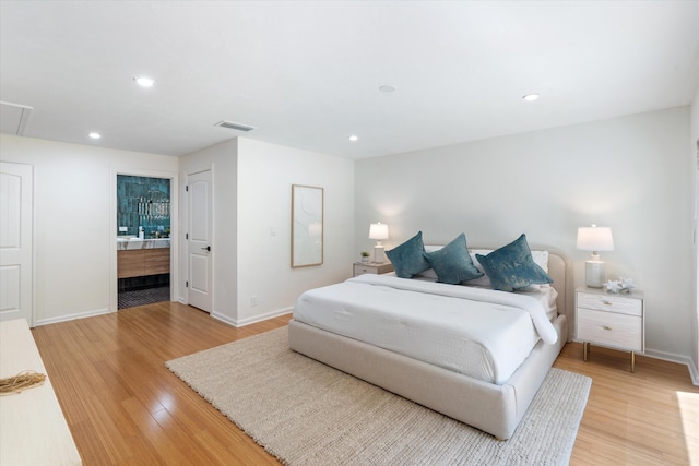 bedroom featuring ensuite bathroom and light hardwood / wood-style flooring