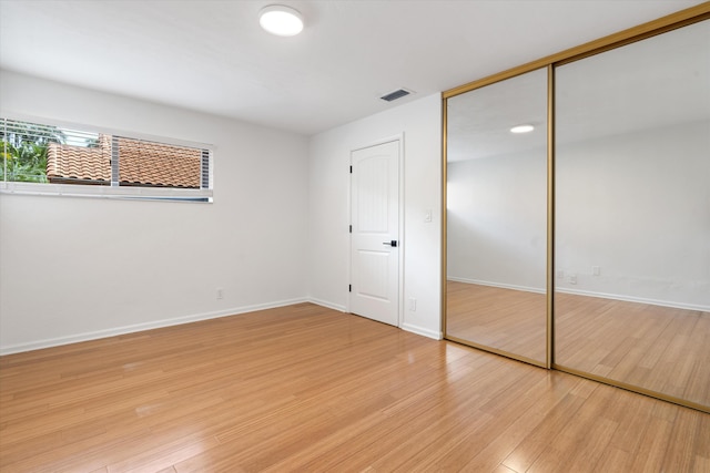 unfurnished bedroom featuring light wood-type flooring and a closet