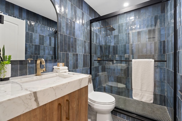 bathroom with toilet, an enclosed shower, vanity, and tile walls