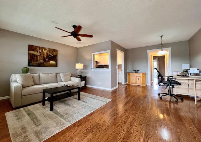 living room featuring a textured ceiling, dark wood-type flooring, and ceiling fan