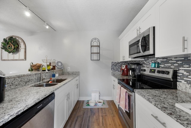 kitchen with sink, a textured ceiling, light stone counters, and appliances with stainless steel finishes