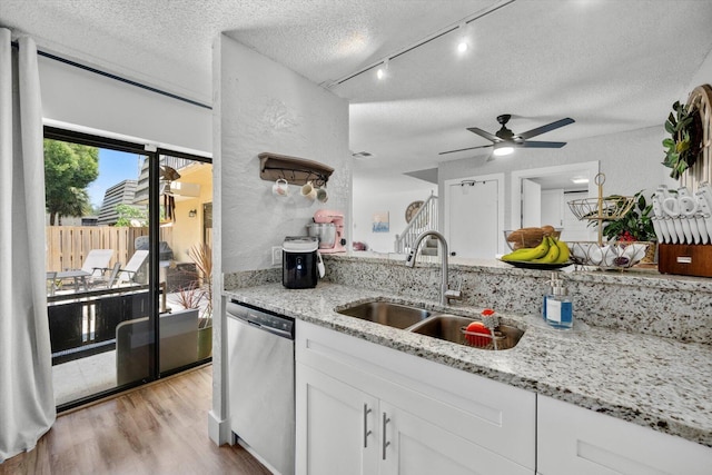 kitchen featuring sink, white cabinets, stainless steel dishwasher, and light stone counters