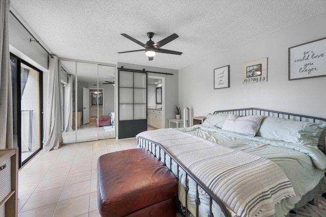 tiled bedroom featuring multiple windows, a textured ceiling, ceiling fan, and a barn door