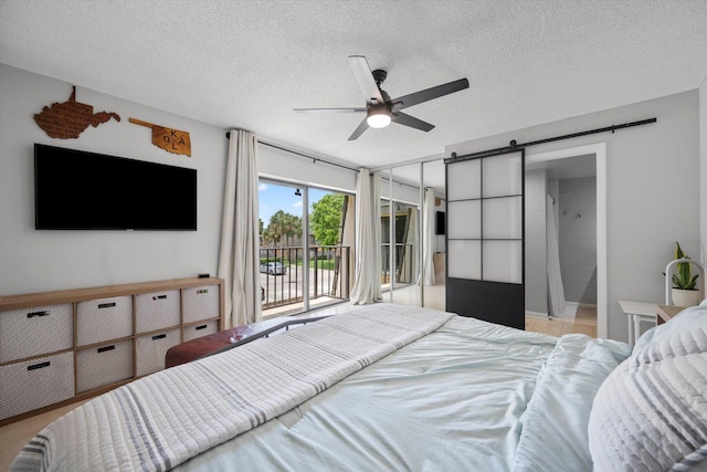 bedroom with a textured ceiling, ceiling fan, access to outside, and a barn door